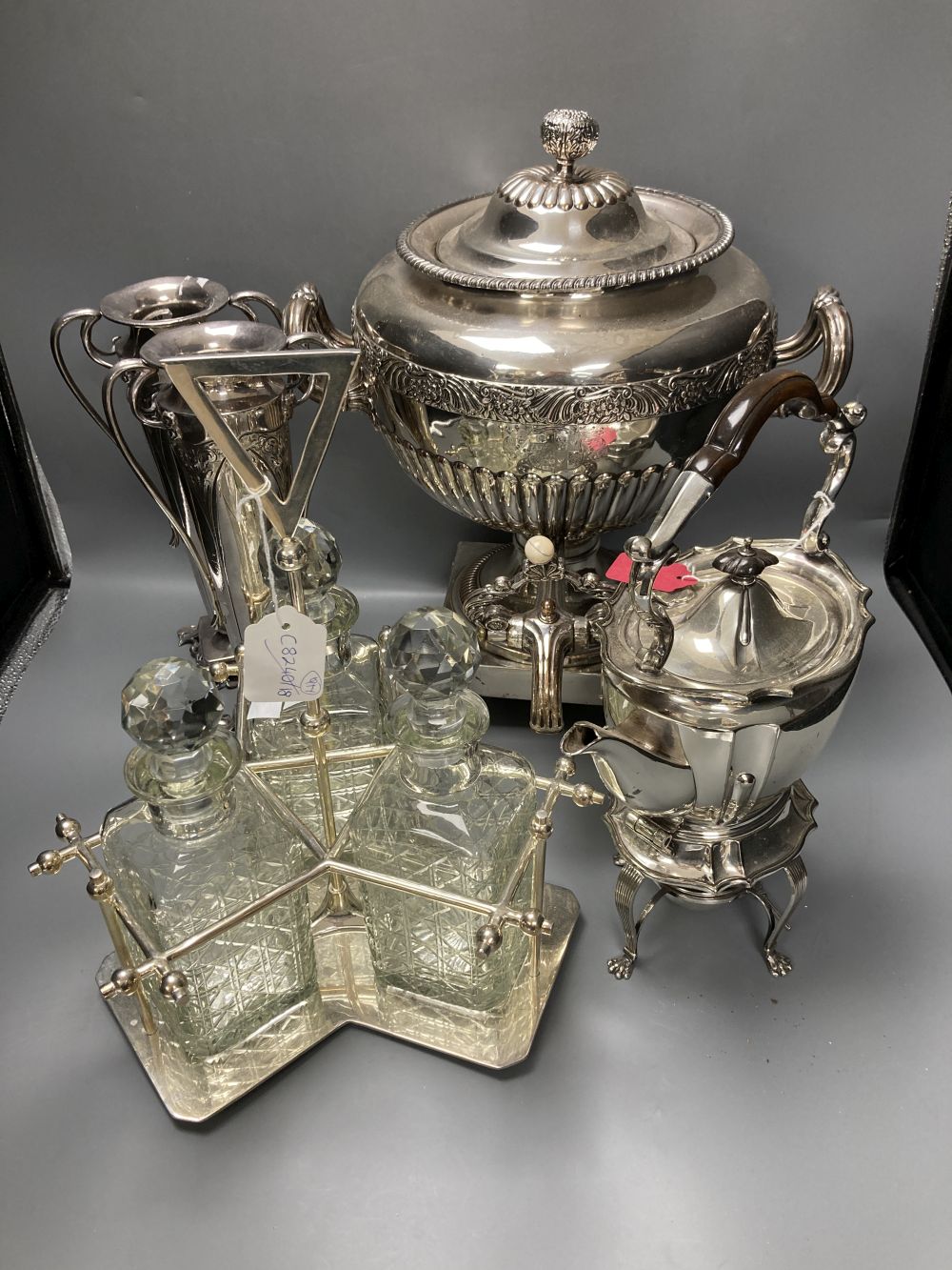 A plated samovar, a kettle on stand, a pair of vases and a three bottle silver plated tantalus and on Old Sheffield plate tea urn, c.18